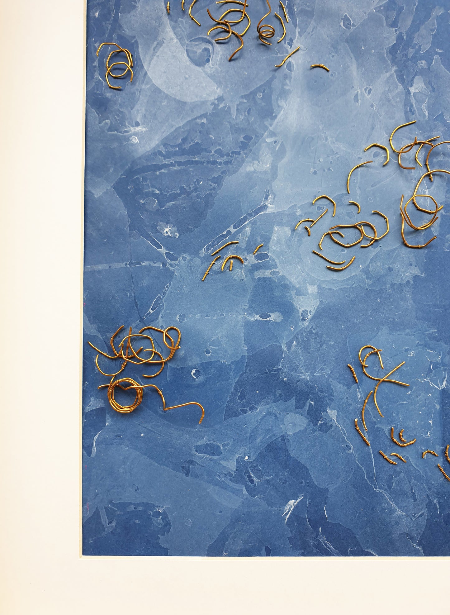 Zoom sur l'oeuvre nommée Eaux Libres. Papier marbré de ton bleue, brodée main avec des fragments de laiton.