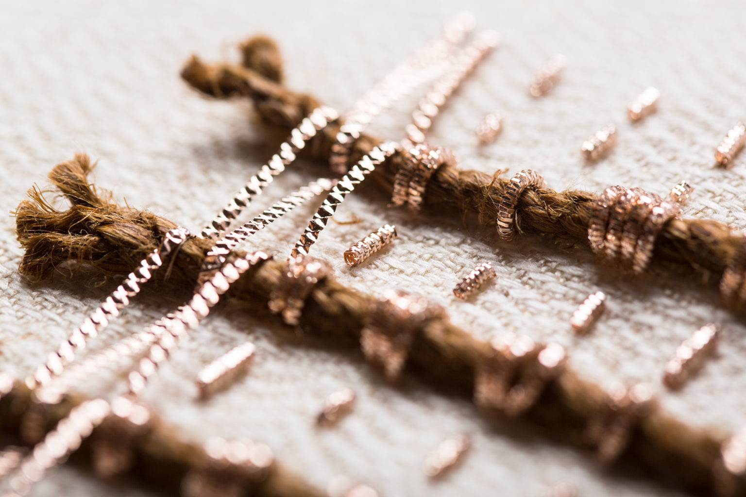 Zoom sur les détails de l'oeuvre intitulée Amulettes. Toile de chanvre et soie brodée main avec des cordes coco et des cannetilles.