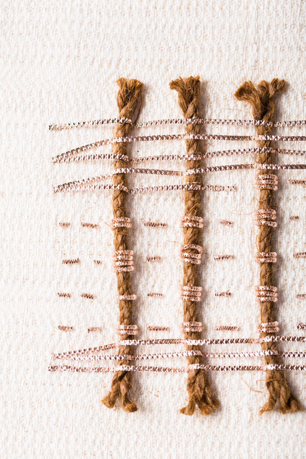 Zoom sur les détails de l'oeuvre intitulée Amulettes. Toile de chanvre et soie brodée main avec des cordes coco et des cannetilles.