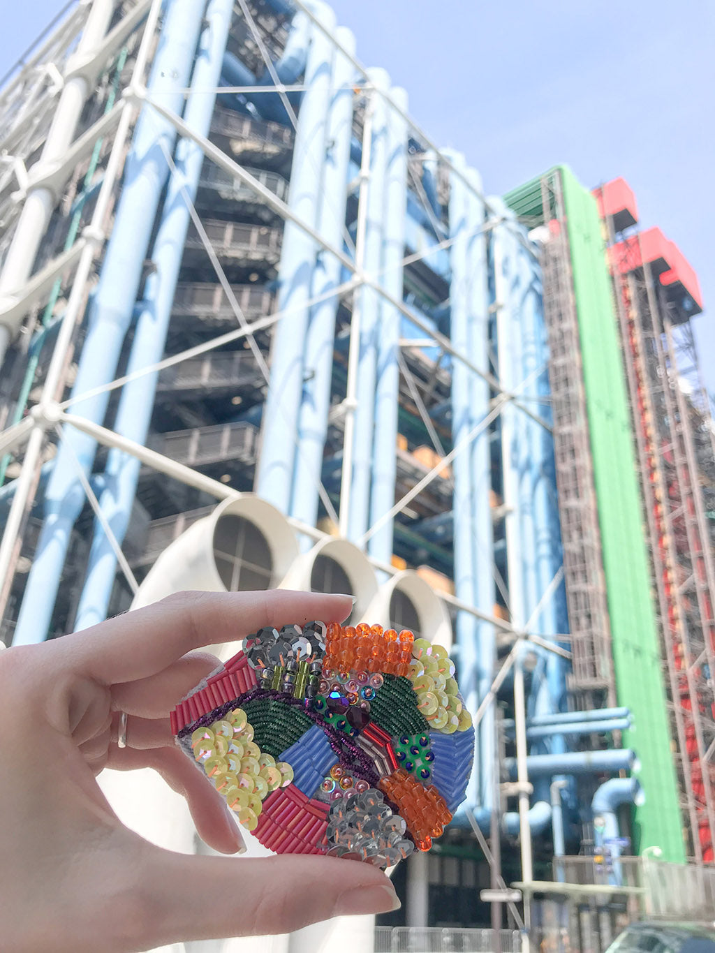 Mise en situation de la broche Paris Arty dans un endroit de Paris qui s'harmonise avec les couleurs de la broche.