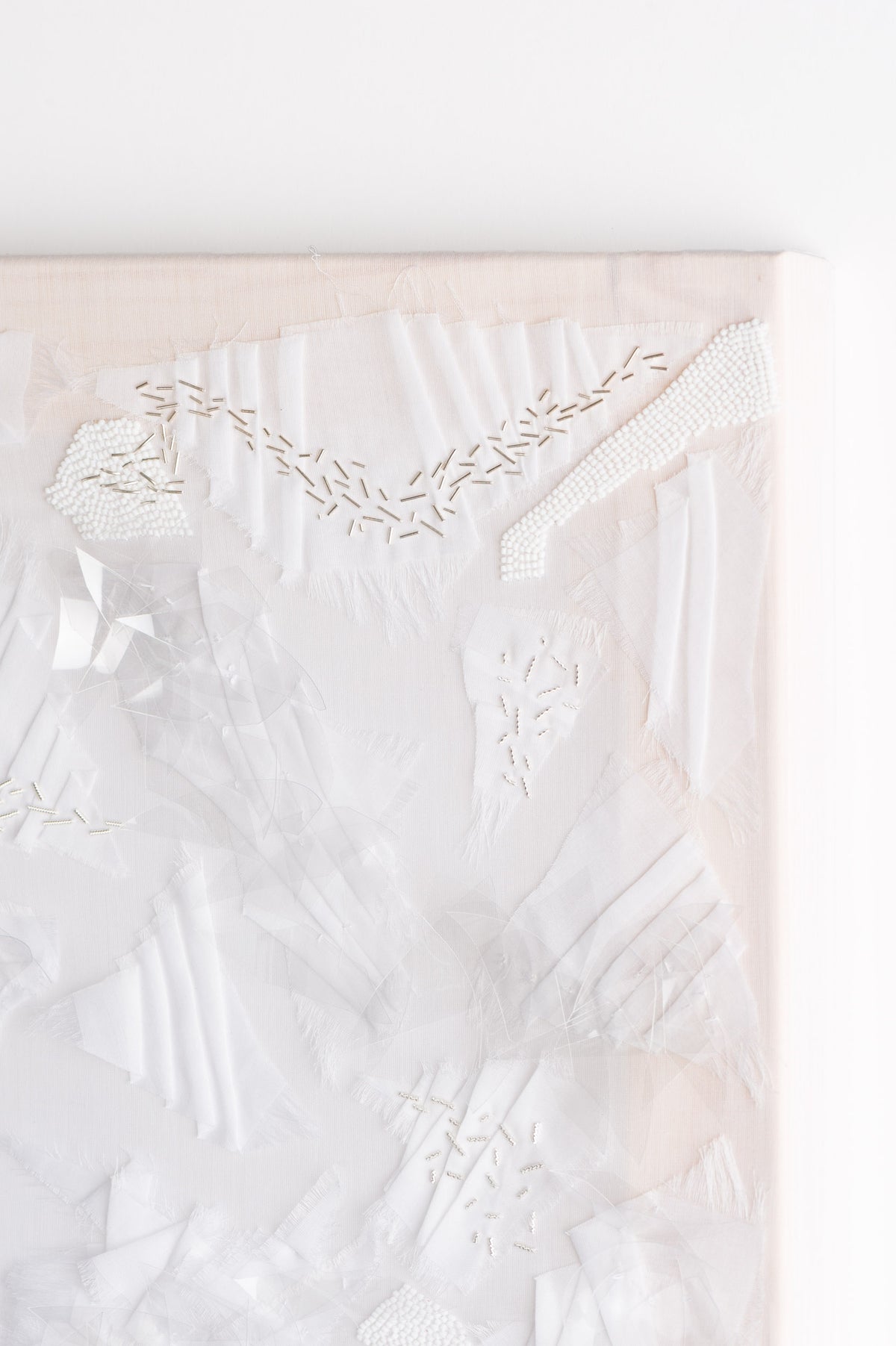 Zoom sur l'oeuvre Opalin. Toile blanche vêtue d'une multitude de fournitures de couleur blanches.