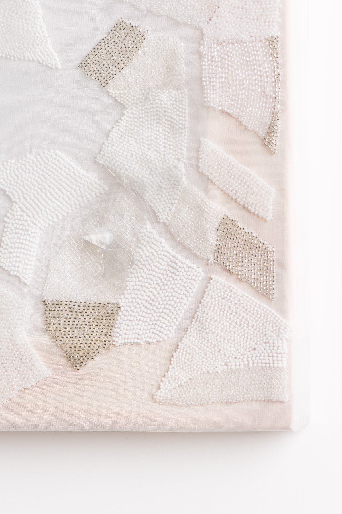 Zoom sur l'oeuvre Opalin. Toile blanche vêtue d'une multitude de fournitures de couleur blanches.