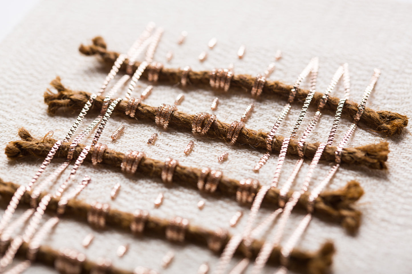 Zoom sur les détails de l'oeuvre intitulée Amulettes. Toile de chanvre et soie brodée main avec des cordes coco et des cannetilles. 
